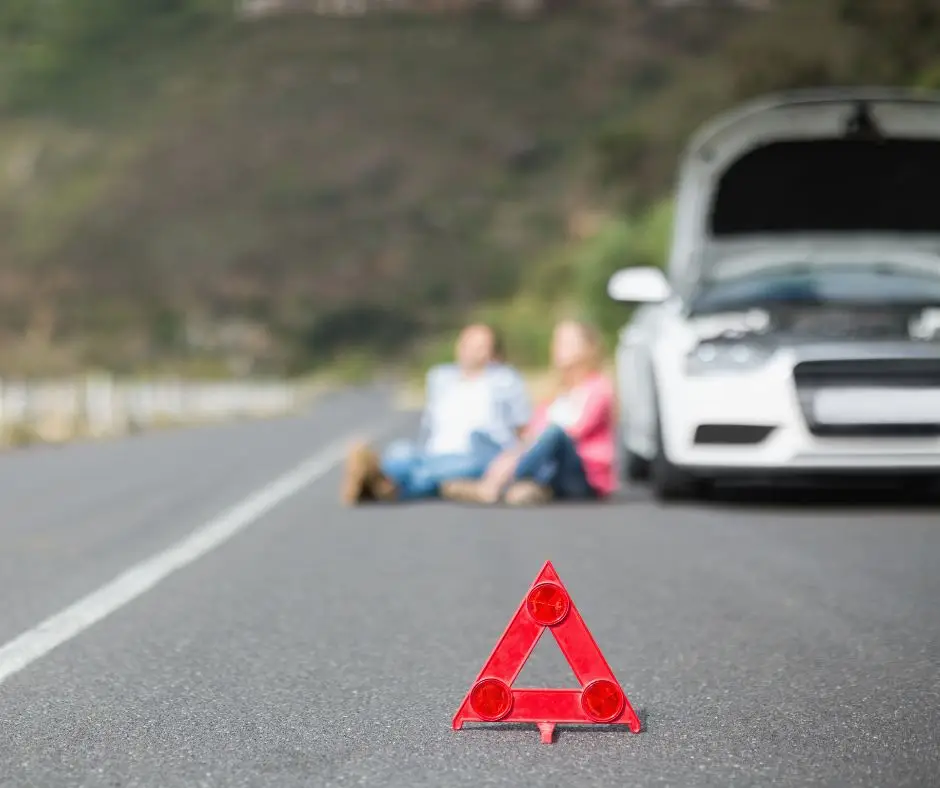 Early warning device with motorists beside a broken down car in the background